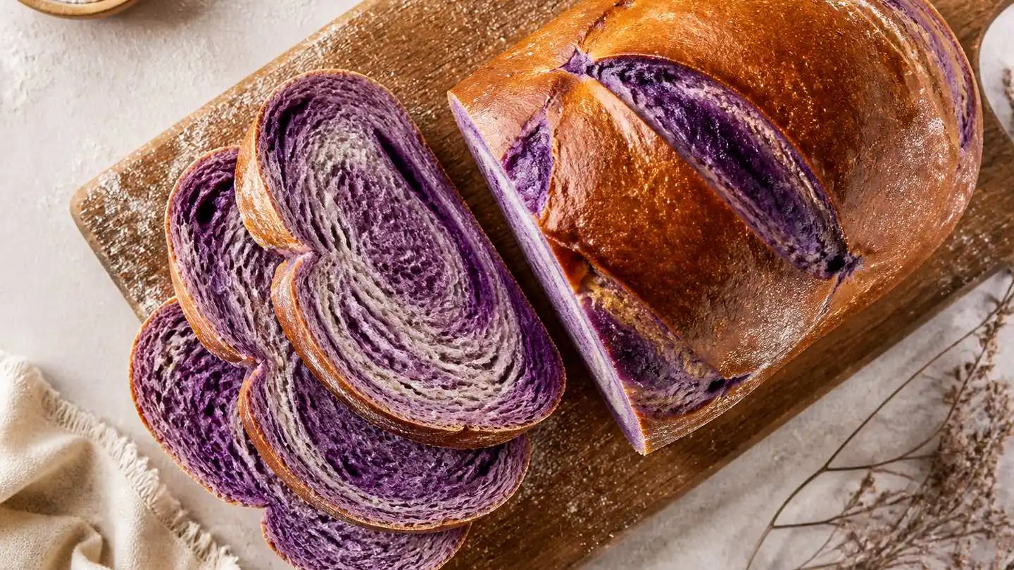 blog-500-1 Sliced loaf of purple ube swirl bread showing a deep violet crumb streaked with lighter swirls and a golden-brown crust