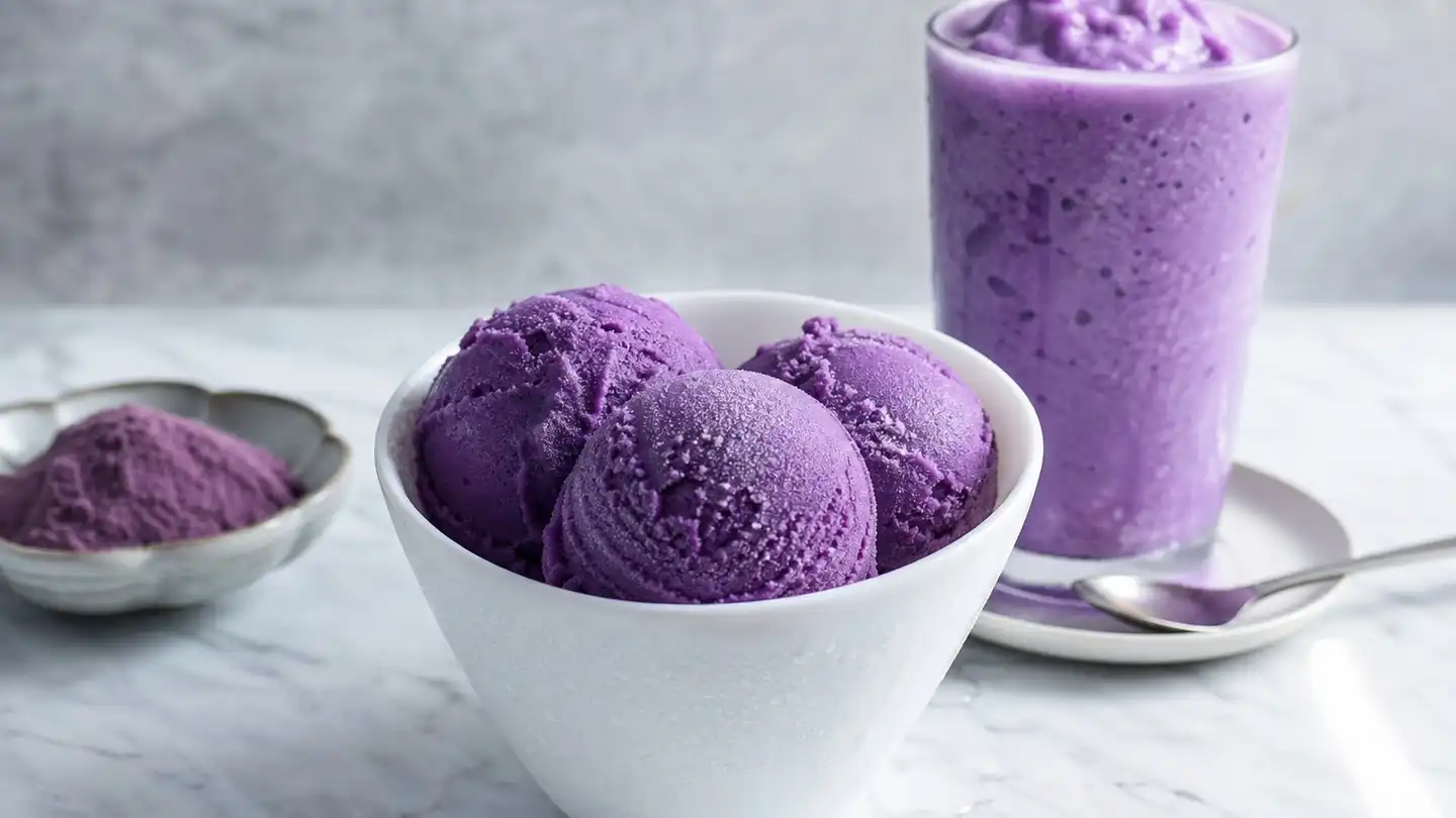 blog-500-1 Three scoops of purple yam ice cream in a white bowl beside a tall glass of purple frozen shake on a marble counter